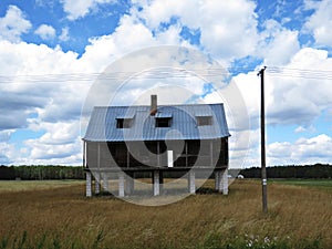 One Single House Standing on Pillars in the Middle of Field