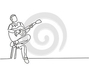 One single line drawing of young happy male guitarist playing acoustic guitar while sitting on chair. Modern musician artist
