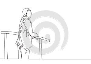 One single line drawing of young happy muslimah wearing head scarf and standing at fence. Beautiful Asian woman model in trendy
