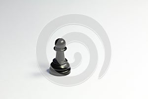 One single lone black pawn chess piece on sad dark white grey background. Loneliness, being alone, abandoned, depression