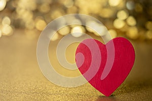 One single red heart on a gold glitter and sequin background that sparkles and has lots of copy space for love