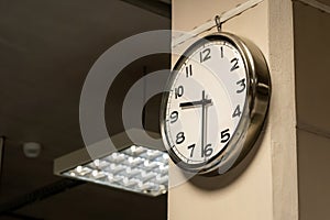 One single simple industrial clock in a factory hall or a corporate office on the wall. Working 9 to 5, clocking in and out, time