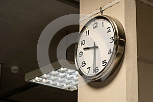 One single simple industrial clock in a factory hall or a corporate office on the wall. Working 9 to 5, clocking in and out, time photo