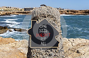 One size does not fit all symbol. Concept words One size does not fit all on beautiful black chalkboard. Beautiful stone sea