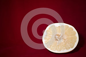 One slice of pomelo on a red table