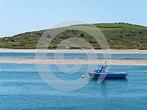 One small boat is anchored in the bay at low tide, a seaside landscape. A boat in shallow water on a sunny day. Irish seascape,