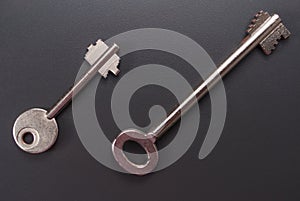 One small and one full-size safe key, safe key on a dark background