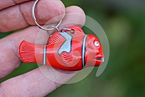 One small red striped plastic keychain toy fish with a flashlight on a chain
