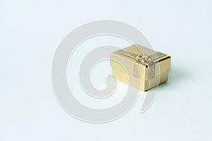 One small square golden gift box with a bow on a white background.