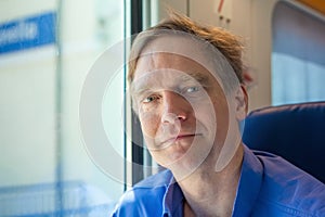 One smiling Caucasian man in forties on commuter train