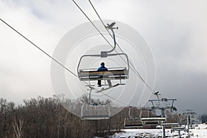 One snowboarder on an empty skilift due to melting snow