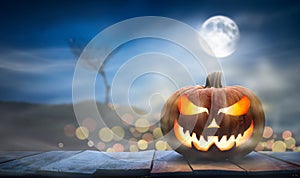 One spooky halloween pumpkin, Jack O Lantern, with an evil face and eyes on a wooden bench.