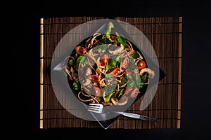 One square plate with Italian vegan integral pasta with broccoli, mushrooms, cherry tomatoes and basil leaves - vegetarian dish