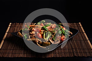 One square plate with Italian vegan integral pasta with broccoli, mushrooms, cherry tomatoes and basil leaves - vegetarian dish