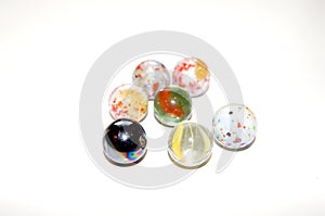 One steel marble together with marbles made of glas and baked clay