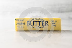 One stick of organic unsalted butter close-up on a light grey background