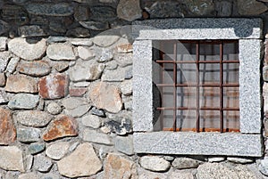 One stone window of a chalet with metal square grates