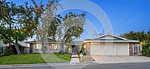 One-story house with front driveway, flanked by two trees in Encino, CA