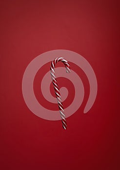 One striped candy cane on red background. Cristmas lollipop