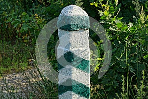 One striped concerte signal pole among the green vegetation