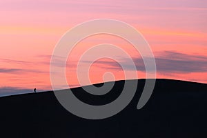 One sunset hiker walking sand dune crest