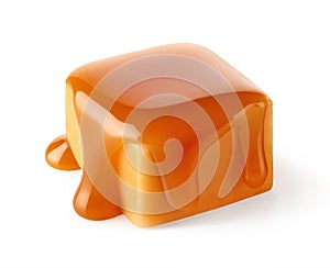 One sweet caramel candy cube topped with caramel sauce on white background