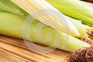 One sweet yellow raw milk corn cobs maize with white granule green fresh ingredient product. Lie wooden background table