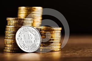 One swiss frank coin and gold money on the desk photo