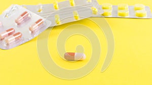 One tablet close-up against other capsules on a yellow background.The concept of medicine.Medicines for the treatment of diseases
