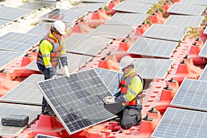 One technician worker stand with hold solar cell panel and the other sit with check and maintenance the panels and stay on base