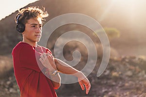 One teenager running or doing jogging alone in the hills - man stretching listen to music with headphones after an exercise