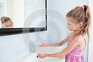 One thin little caucasian girl washing her hands in bathroom during morning hygienic procedure