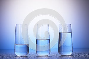 One-third, half-filled and two-thirds full drinking glasses