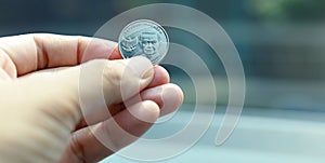 One thousand rupiah coins,man hand holding one rupiah coins  on a blurred background. Indonesian rupiah currency