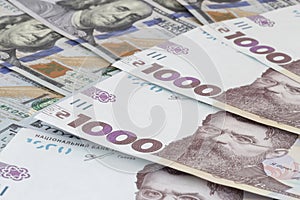 one thousand Ukrainian hrivnya banknotes lying on US dollars banknotes