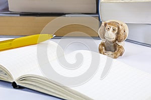 One tired toy monkey with notepad and pencil and many thick books