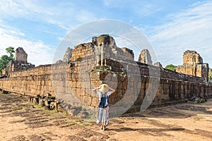 One tourist visiting Angkor Wat ruins at sunrise, Pre Rup temple, travel destination Cambodia. Woman with traditional hat and