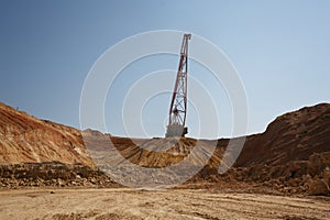 One-tower metal mobile crane on a blue sky background. An industrial moving machine in the foundation pit. Copy space.