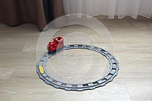 One toy train stands on the rails on the floor in the house