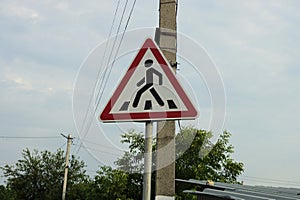 One triangular road sign pedestrian crossing on a pillar on a street