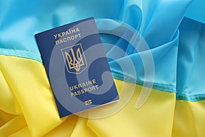 One Ukrainian biometrical passport on folded waving flag of Ukraine country