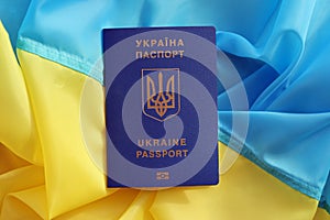 One Ukrainian biometrical passport on folded waving flag of Ukraine country