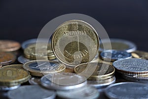 One Ukrainian hryvnia coin stands on coins of other countries