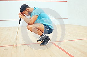 One unknown athletic squash player crouching and feeling sad and stressed after playing game on court. Fit active mixed