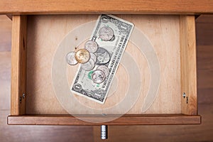 One US Dollar and coins in open drawer