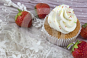 One vanilla cupcake with white cream and several strawberries