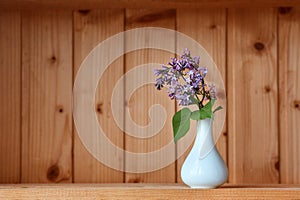 One vase with flowers at wooden background