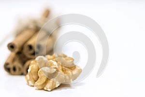 One walnut and cinnamon sticks on a white background, close up