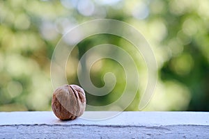 One walnut lies on a white surface, abstract background banner, beautiful round bokeh, concept of harmony of nature, high-calorie