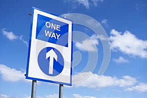 One way directional arrow sign against blue sky